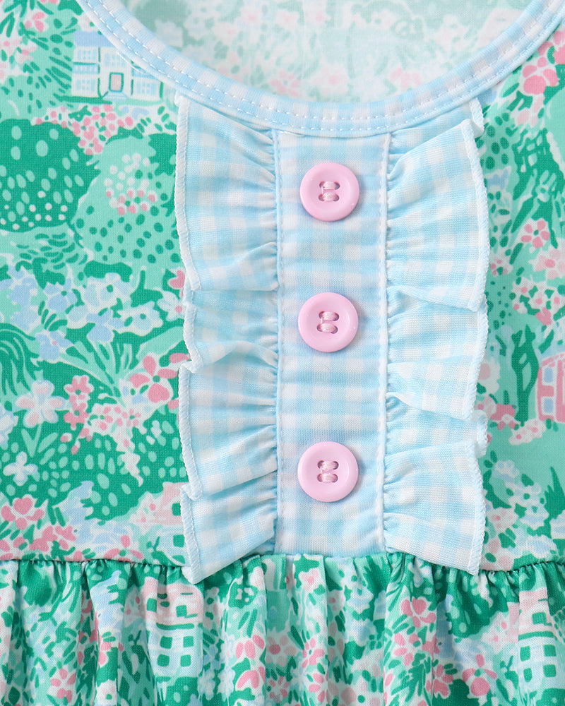 Close-up of a dress with floral pattern and pink buttons on a green background