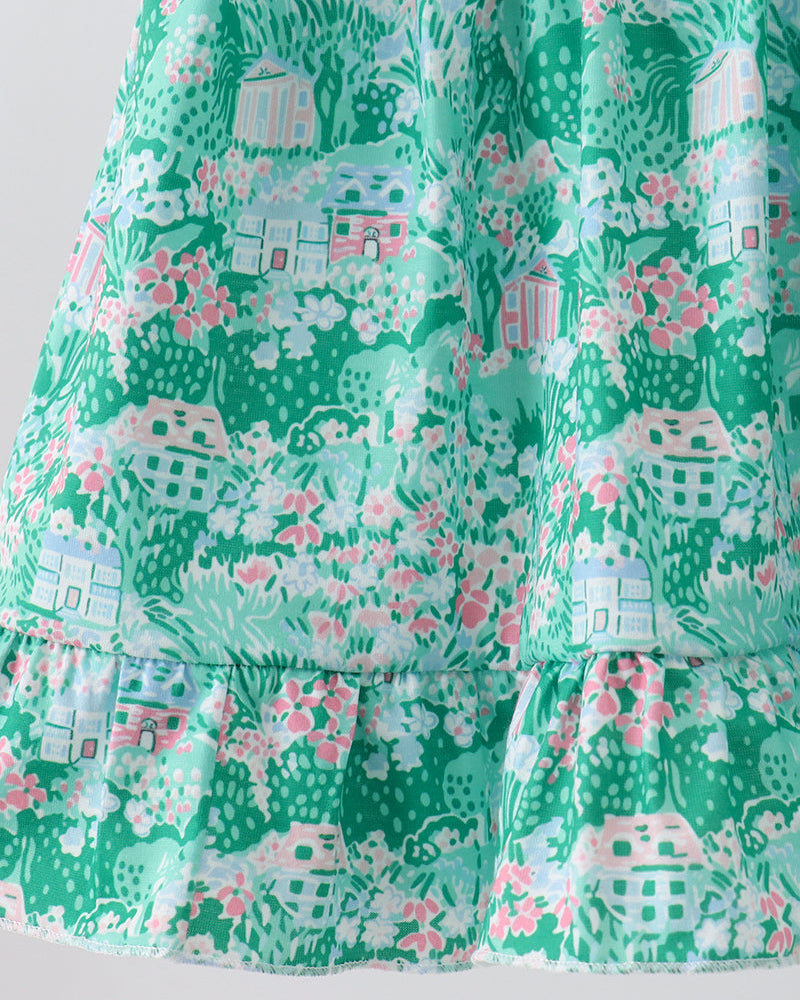 Green fabric with a pattern of small houses and flowers on a white background