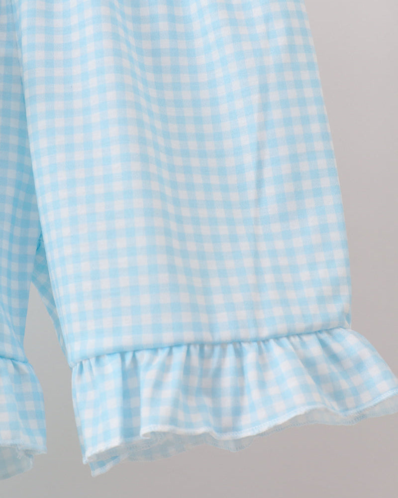 Light blue checkered fabric with ruffled hem on a gray background