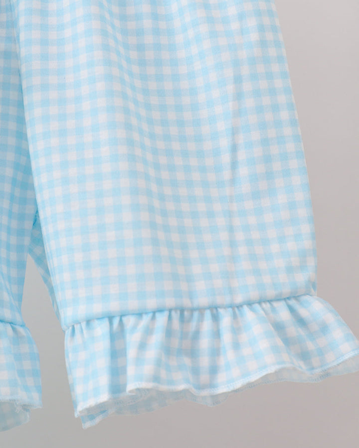 Light blue checkered fabric with ruffled hem on a gray background