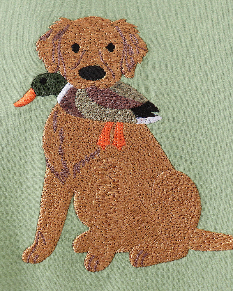 Embroidered dog with a duck on green fabric