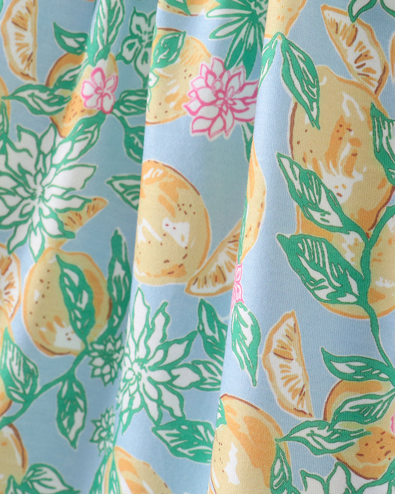Fabric with a pattern of lemons, leaves, and flowers on a light blue background