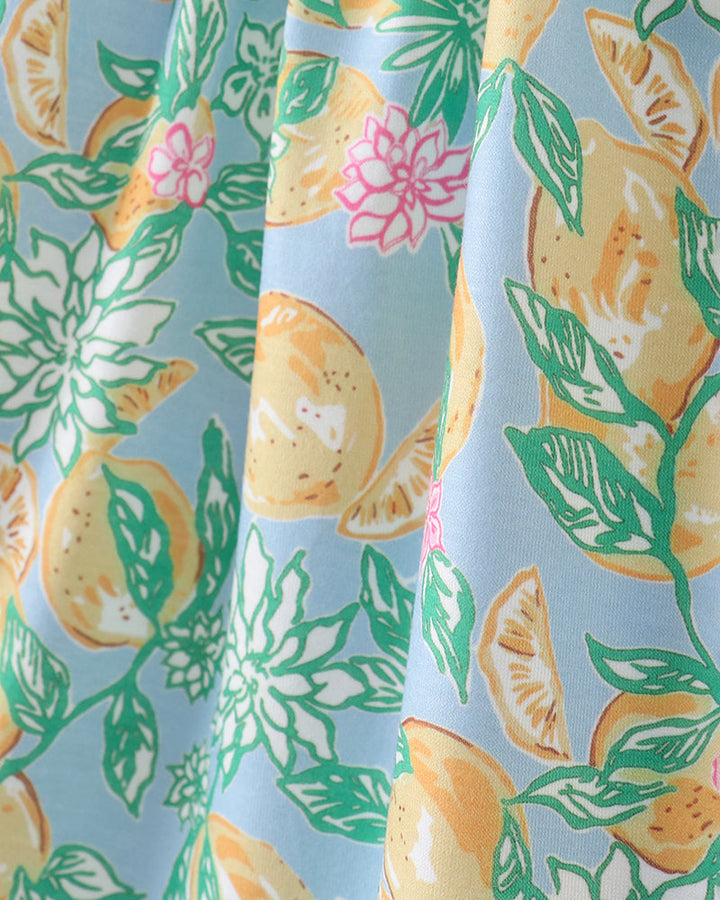 Fabric with a pattern of lemons, leaves, and flowers on a light blue background