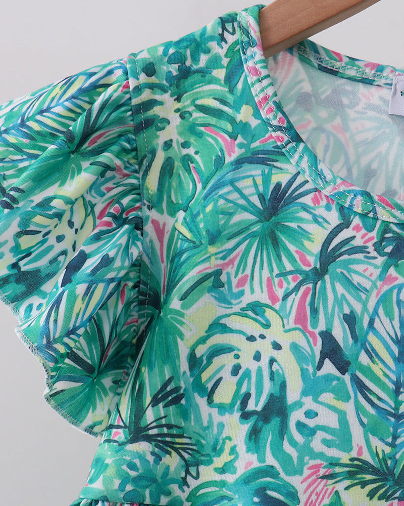 Baby dress fabric close-up with green and teal tropical leaf floral print