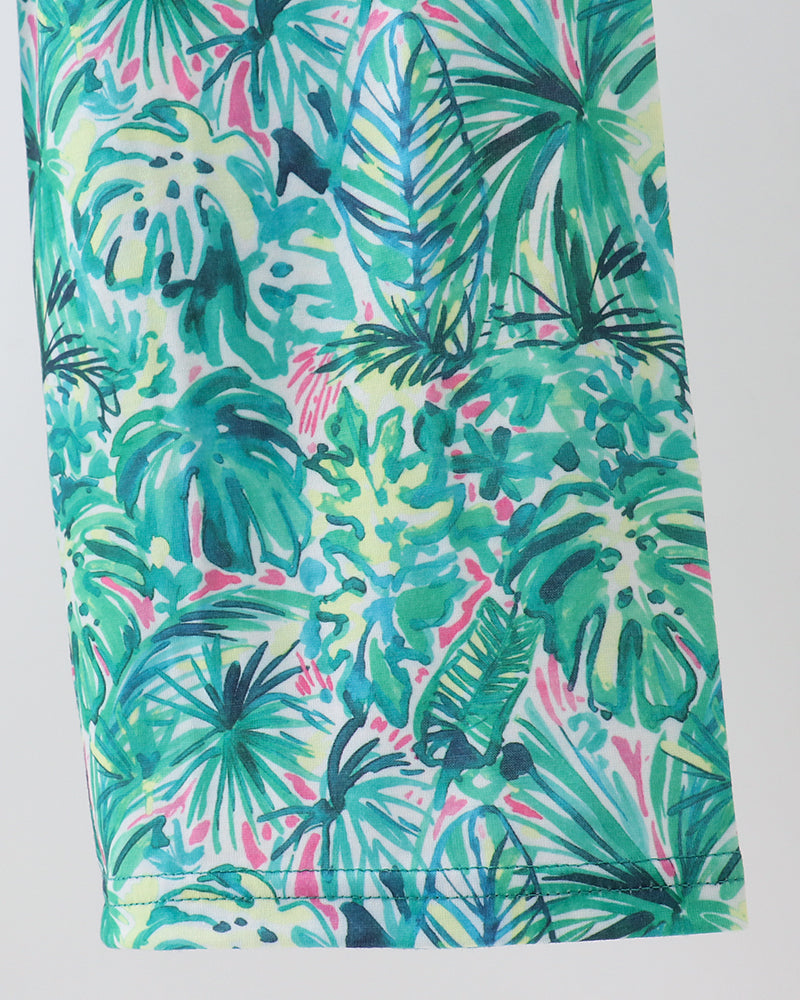 Green Lily floral jumpsuit leg close-up with teal and pink tropical leaf print