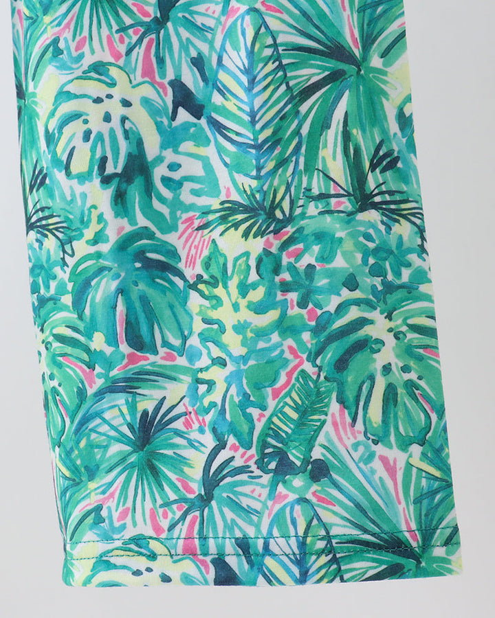 Green Lily floral jumpsuit leg close-up with teal and pink tropical leaf print