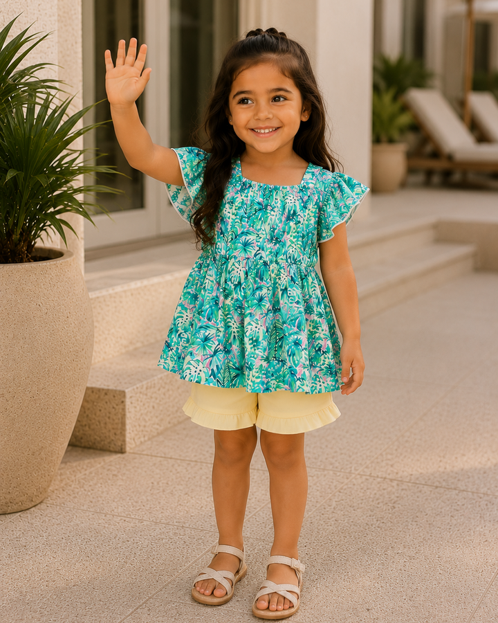 Turquoise floral flutter-sleeve dress with yellow ruffle shorts, worn with sandals