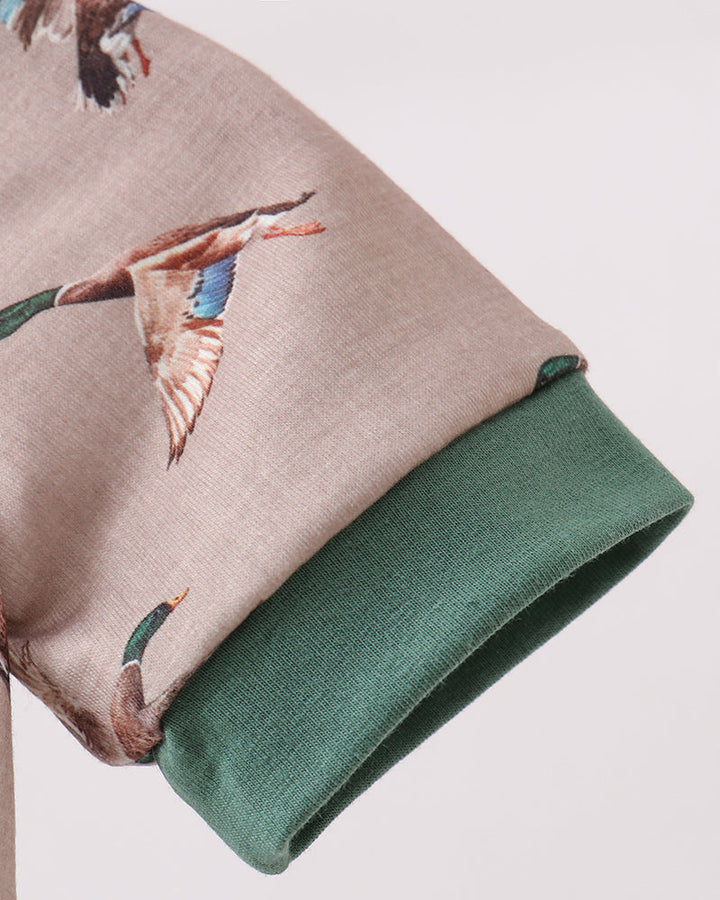 Close-up of a fabric with bird embroidery on a beige and green background