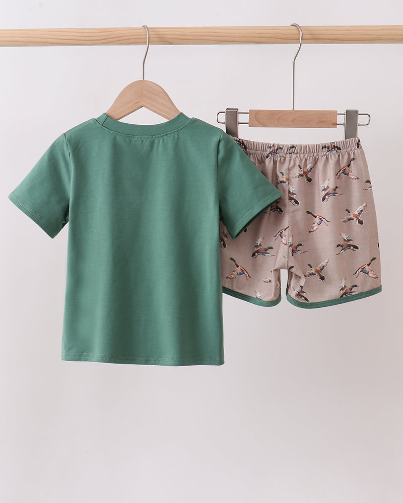 Green t-shirt and patterned shorts hanging on a rack against a white background