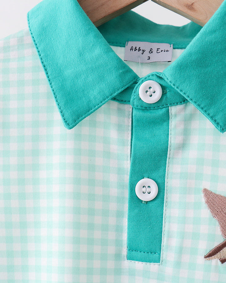 Close-up of a green checkered shirt with a collar and buttons, featuring the brand &