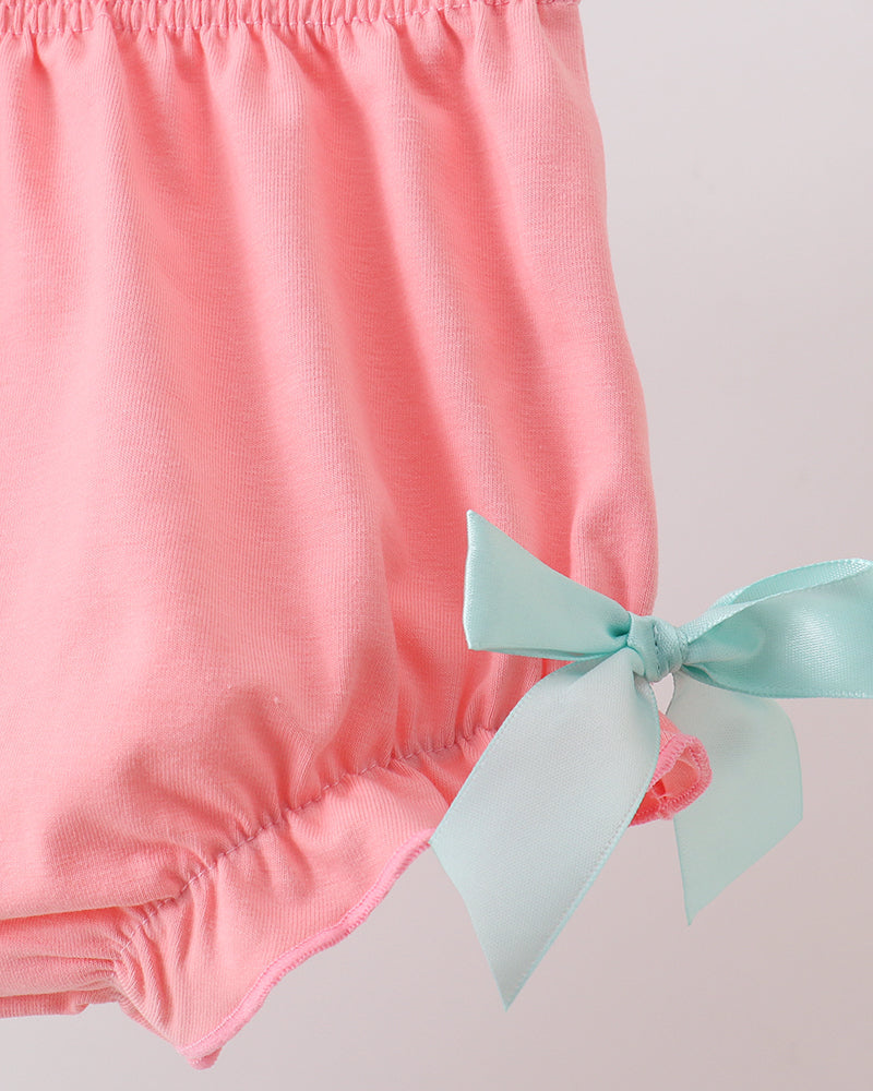 Pink baby bloomers with a light blue bow on a light gray background