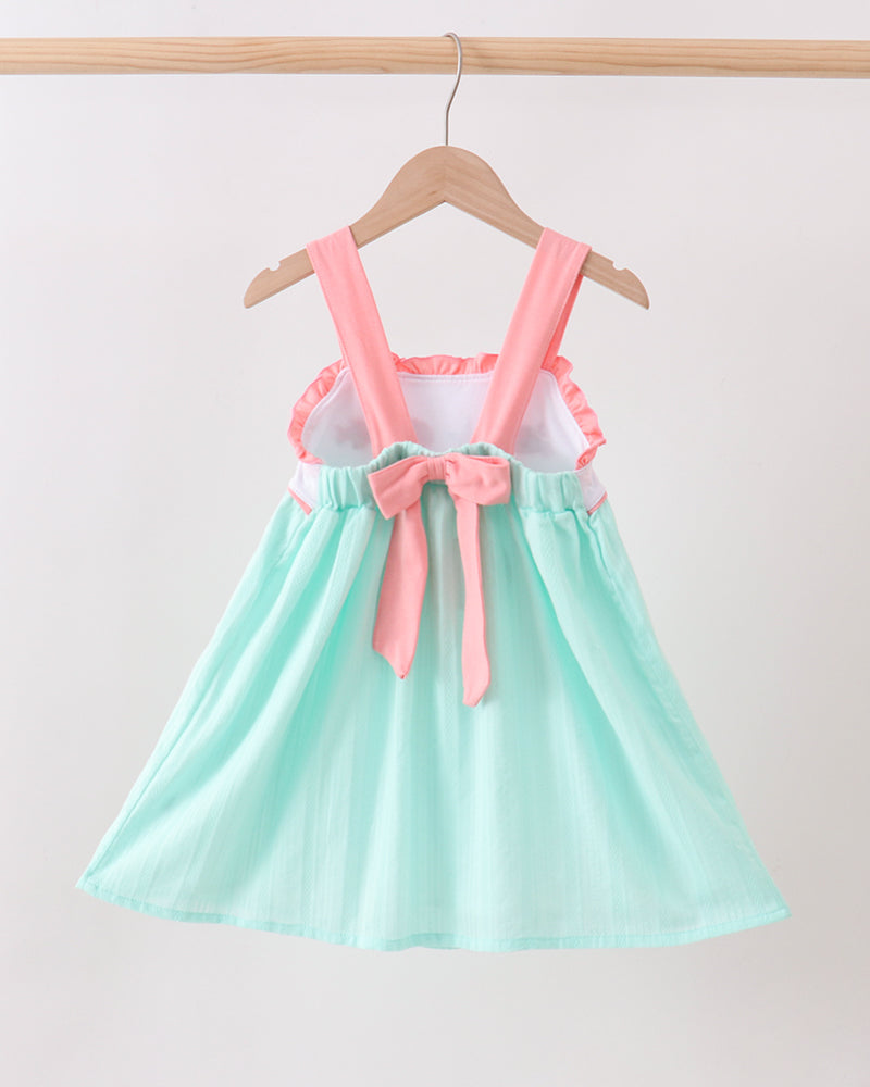 Mint green dress with pink suspenders and bow on a hanger against a white background