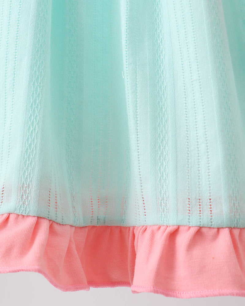 Close-up of a fabric with a light blue top and pink bottom on a gray background