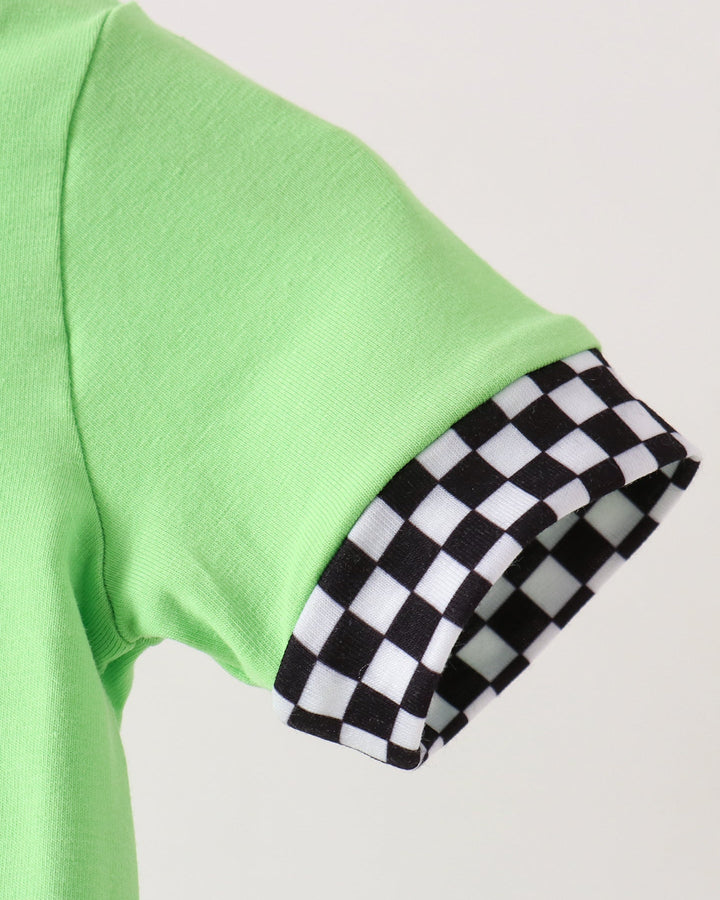 Close-up of a bright lime green short-sleeve top with a black and white checkered patterned cuff.