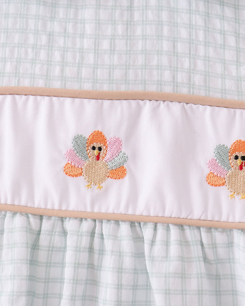 Plaid bodice with embroidered turkey motif on white ruffle hem panel
