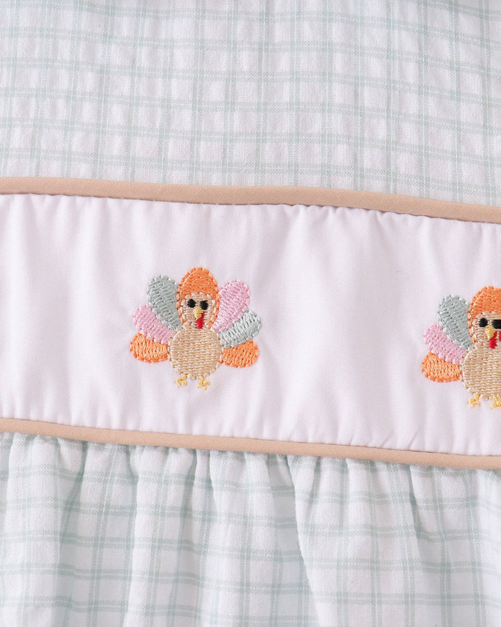 Plaid bodice with embroidered turkey motif on white ruffle hem panel