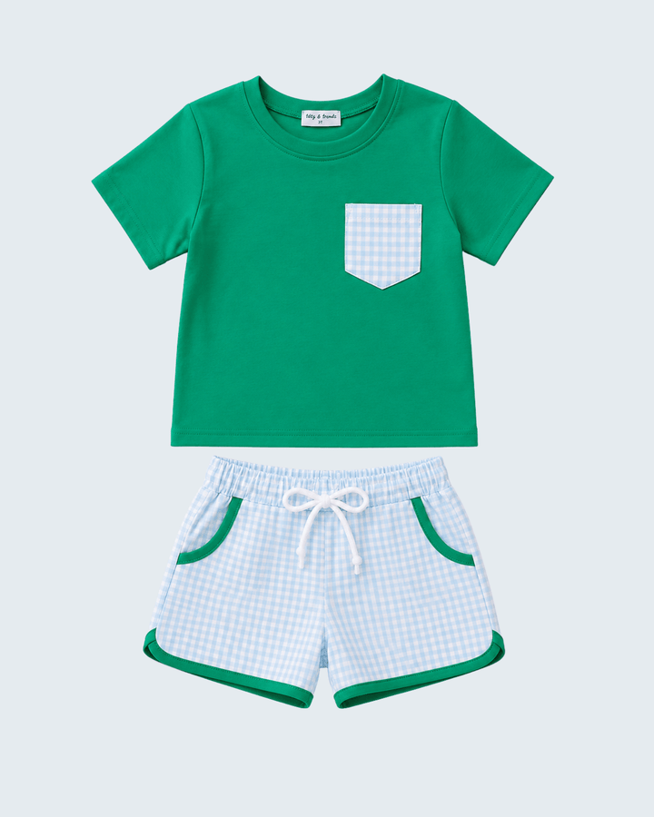 Green t-shirt with a pocket and checkered shorts on a light blue background