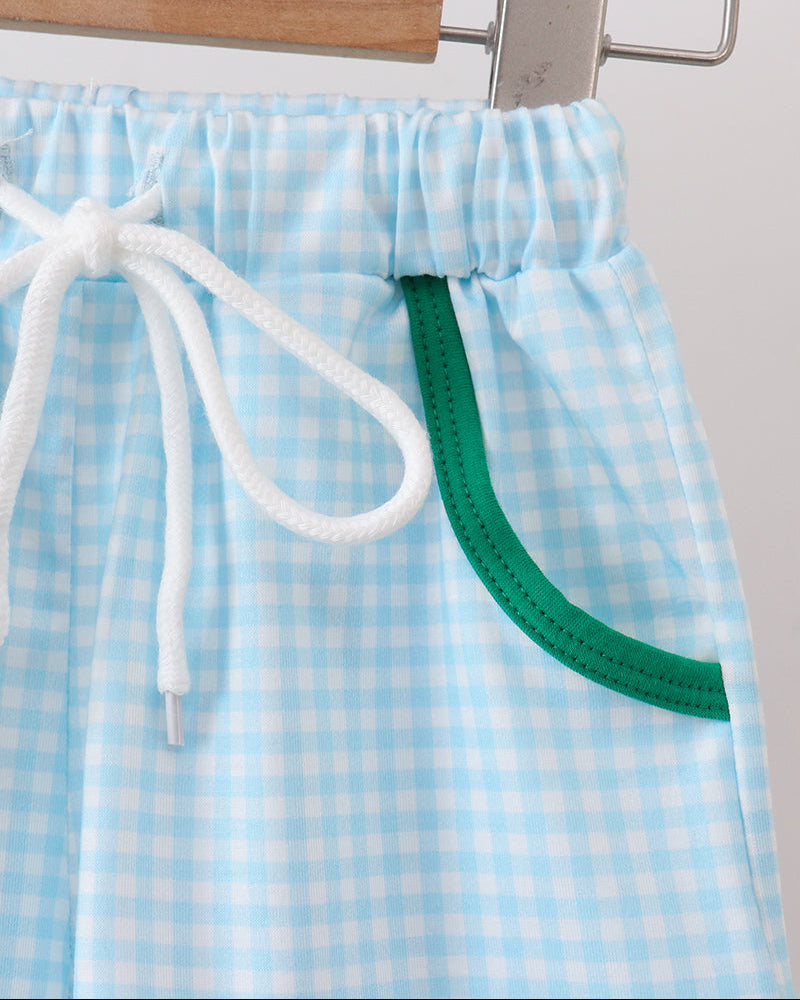 Blue and white checkered shorts with a green belt and white drawstring on a hanger.