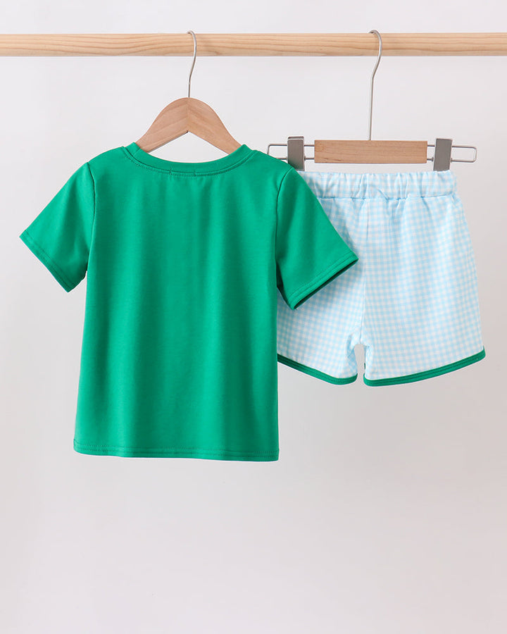Green t-shirt and checkered shorts on hangers against a white background