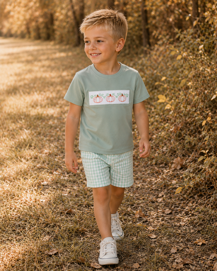Young boy walking at the edge of a row of trees. 