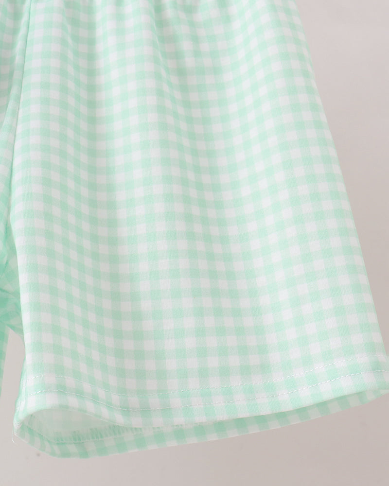 A close-up of a mint green and white gingham checkered fabric, showing the texture and pattern against a light neutral background.