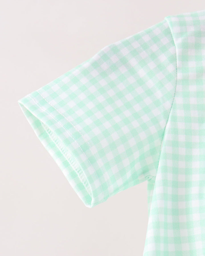 Close-up of a mint green and white gingham patterned short-sleeve garment, showing the fabric texture and collar detail against a plain light background.