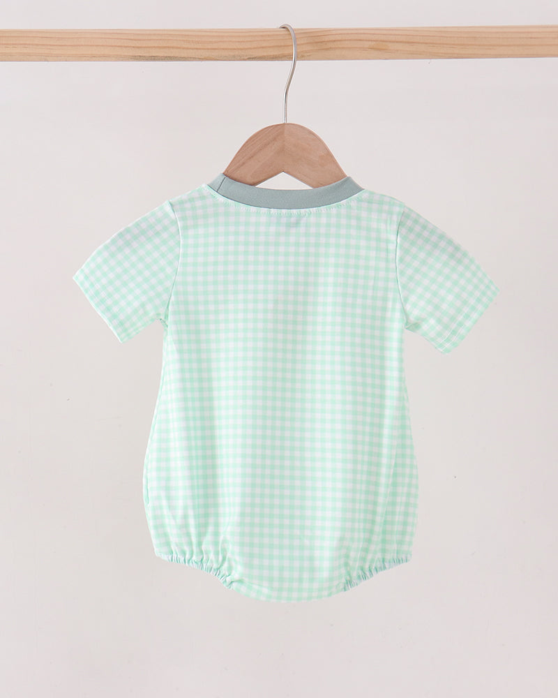 A baby short-sleeve romper in a light mint green and white gingham check pattern, hanging on a wooden hanger from a wooden clothes rack against a plain off-white background.