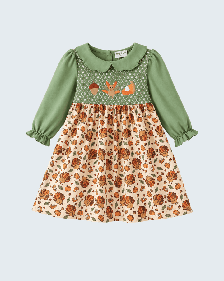 Green smocked yoke dress with long puff sleeves and pumpkin/turkey patterned skirt