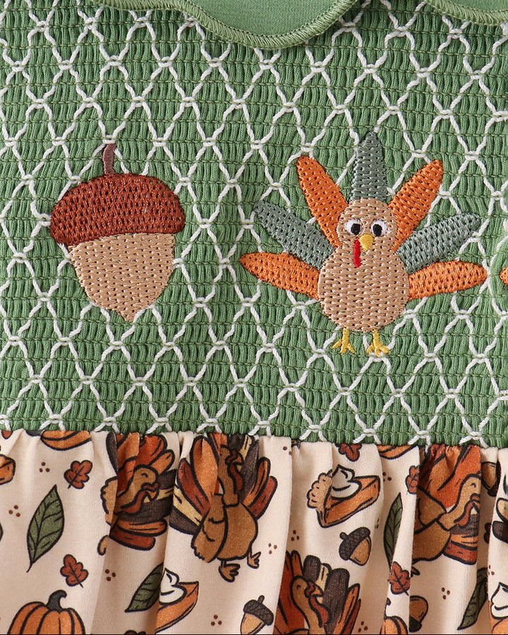 Green smocked yoke with embroidered turkey and pumpkin motifs