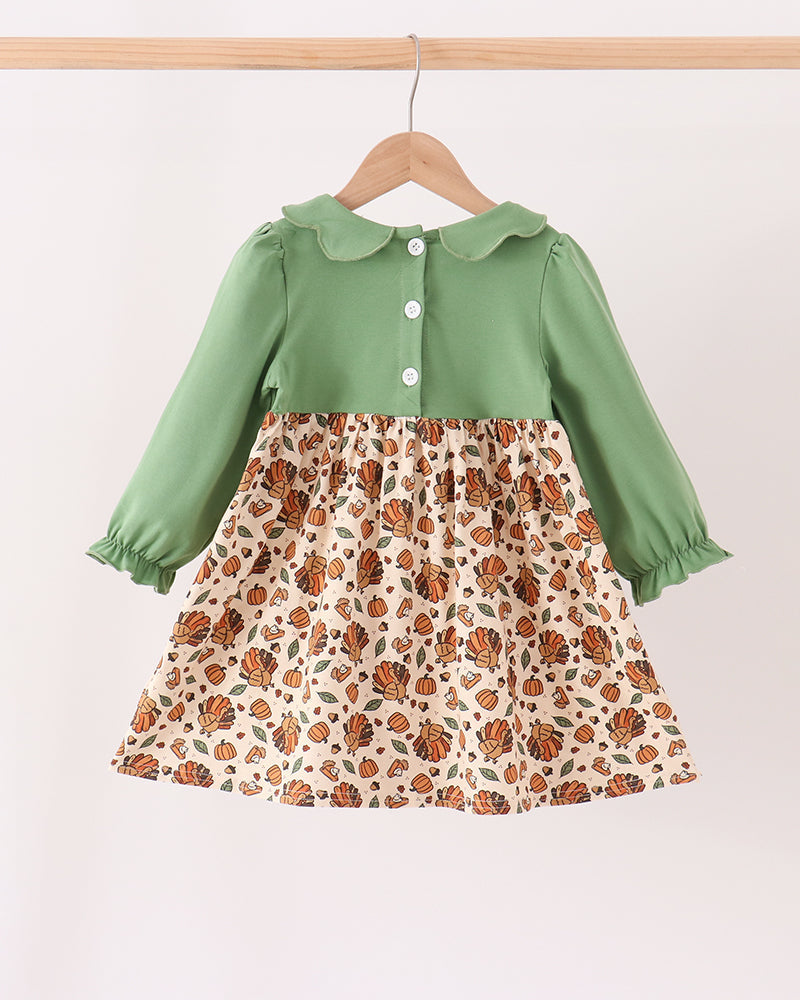 Green long-sleeve button front smocked dress with patterned pumpkin print skirt