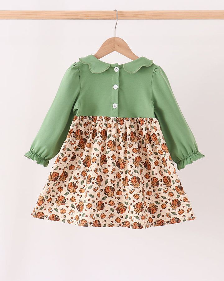Green long-sleeve button front smocked dress with patterned pumpkin print skirt