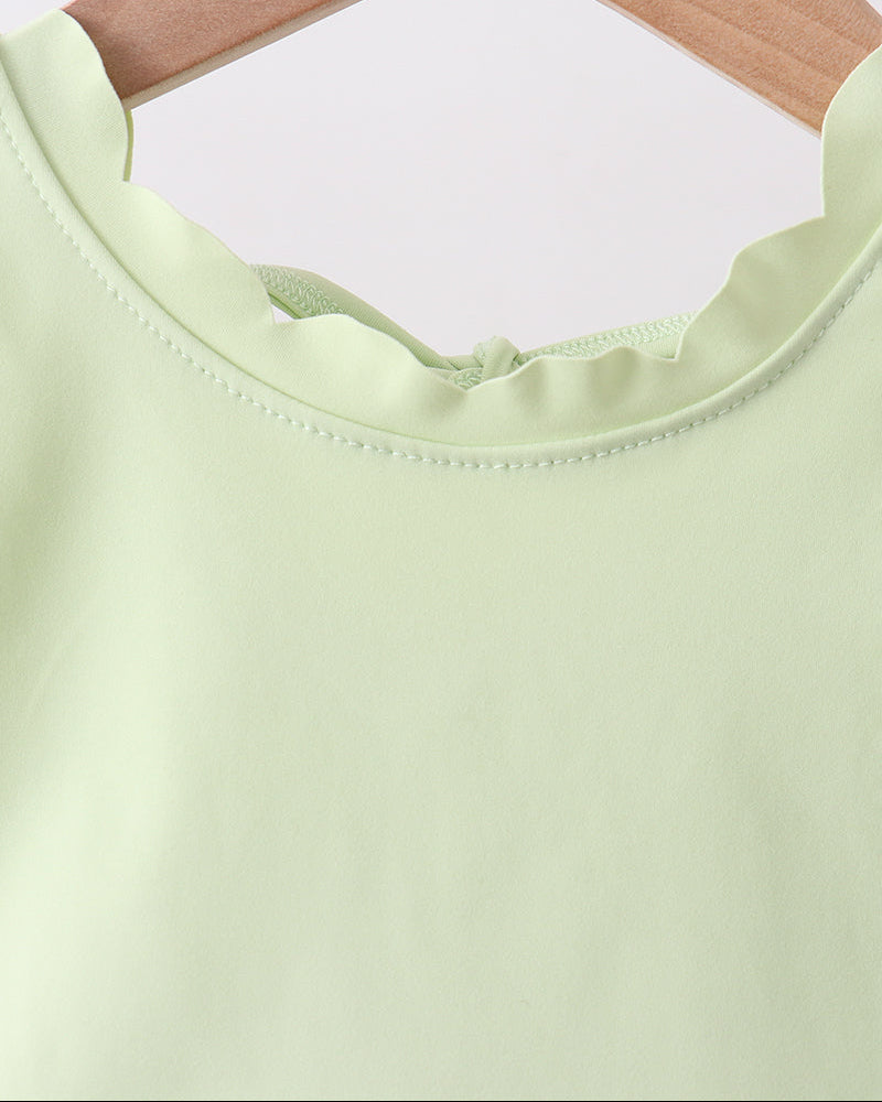 Light green top on a wooden hanger against a white background