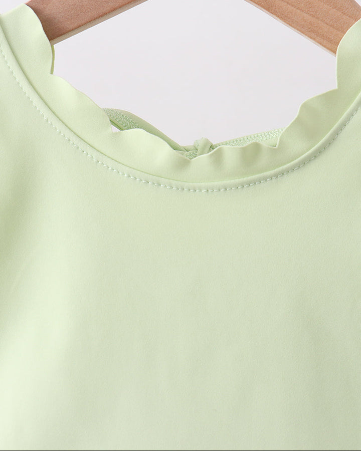 Light green top on a wooden hanger against a white background