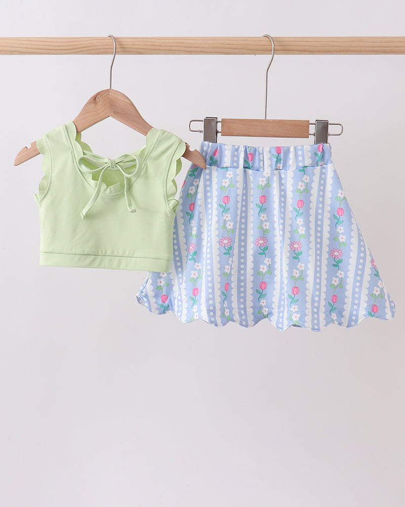 Green top and blue floral skirt on hangers against a white background