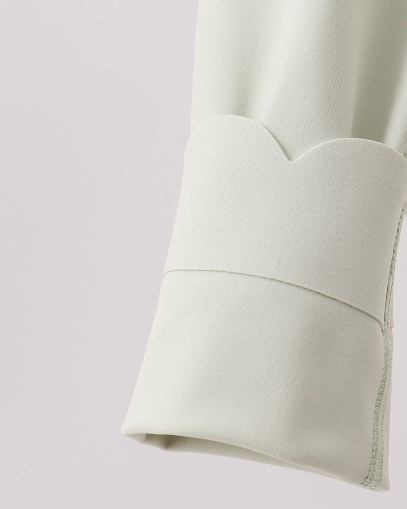 Close-up of a light green fabric with a subtle pattern on a light purple background
