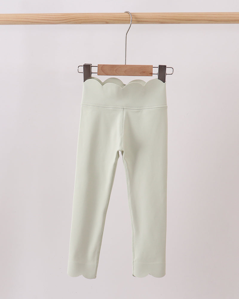 Light green pants hanging on a wooden hanger against a white background