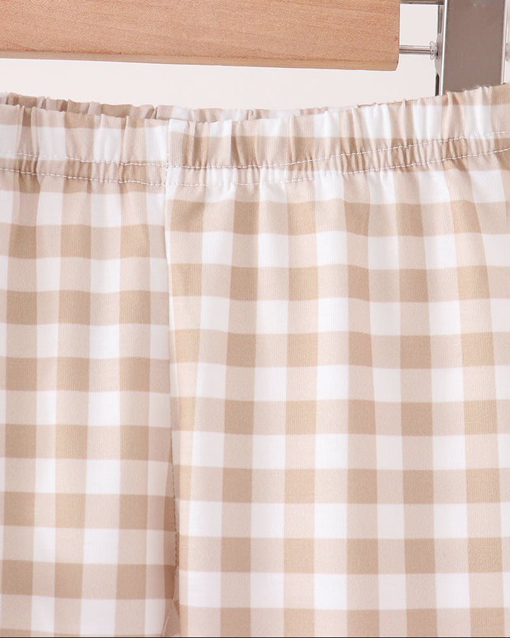 Close-up of beige and white gingham checkered fabric, likely a curtain or drape, hanging from a wooden hanger.
