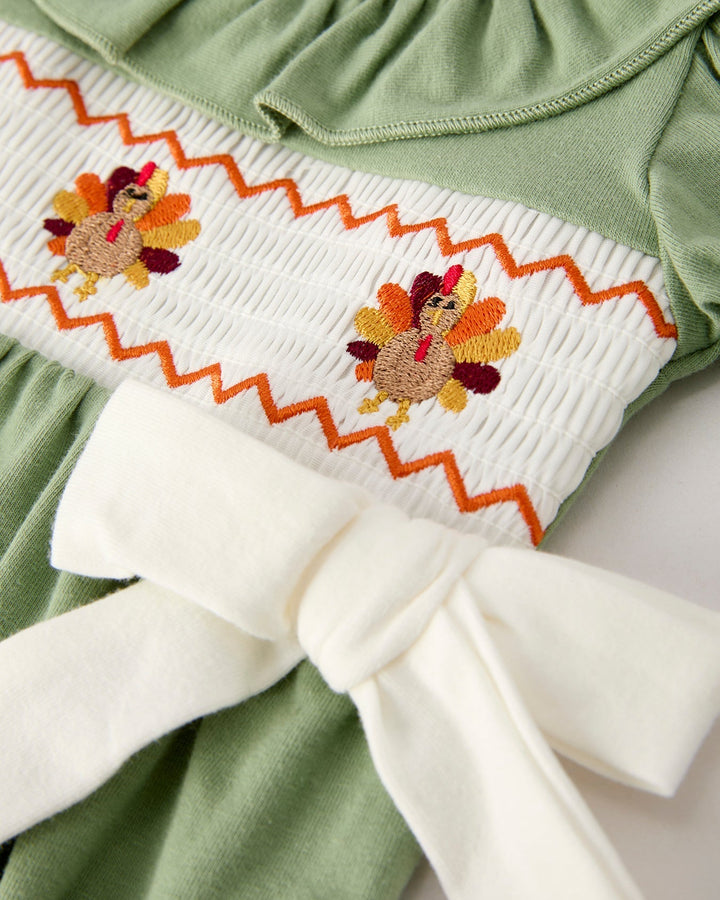 Green romper with white yoke panel and orange floral embroidery