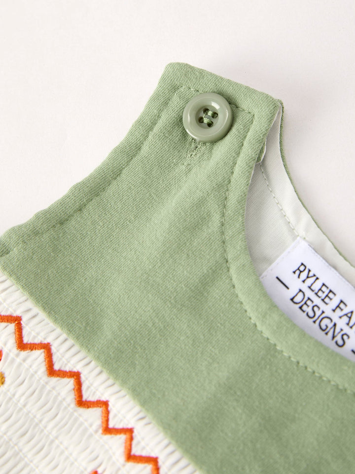 Light green romper neckline with button and contrast orange-trimmed yoke edge