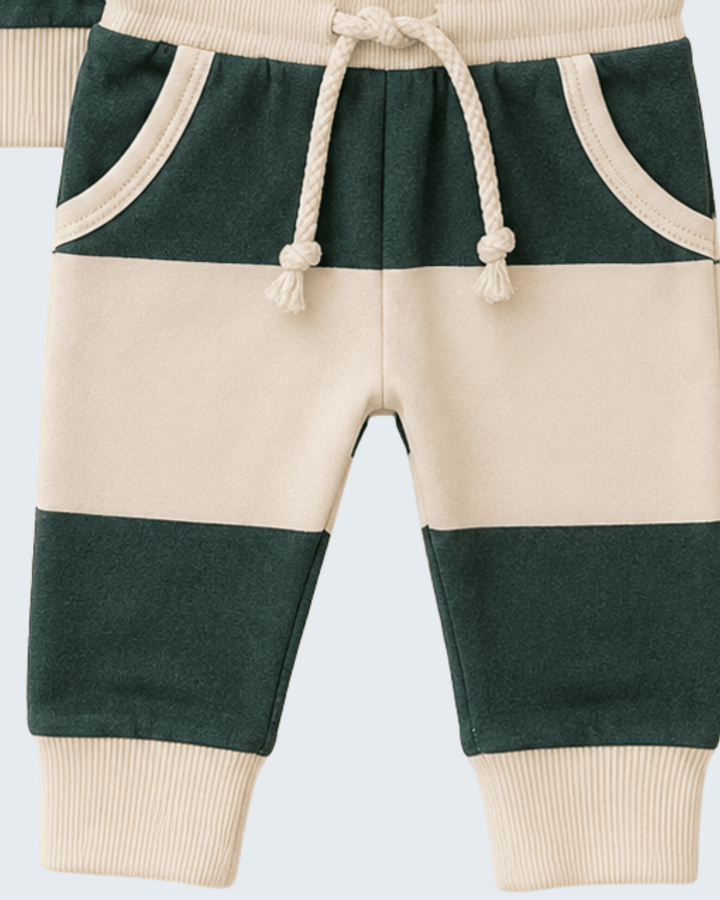 A close-up of a pair of color-blocked baby pants with horizontal stripes of dark green and cream, featuring a cream drawstring waist and ribbed cuffs.
