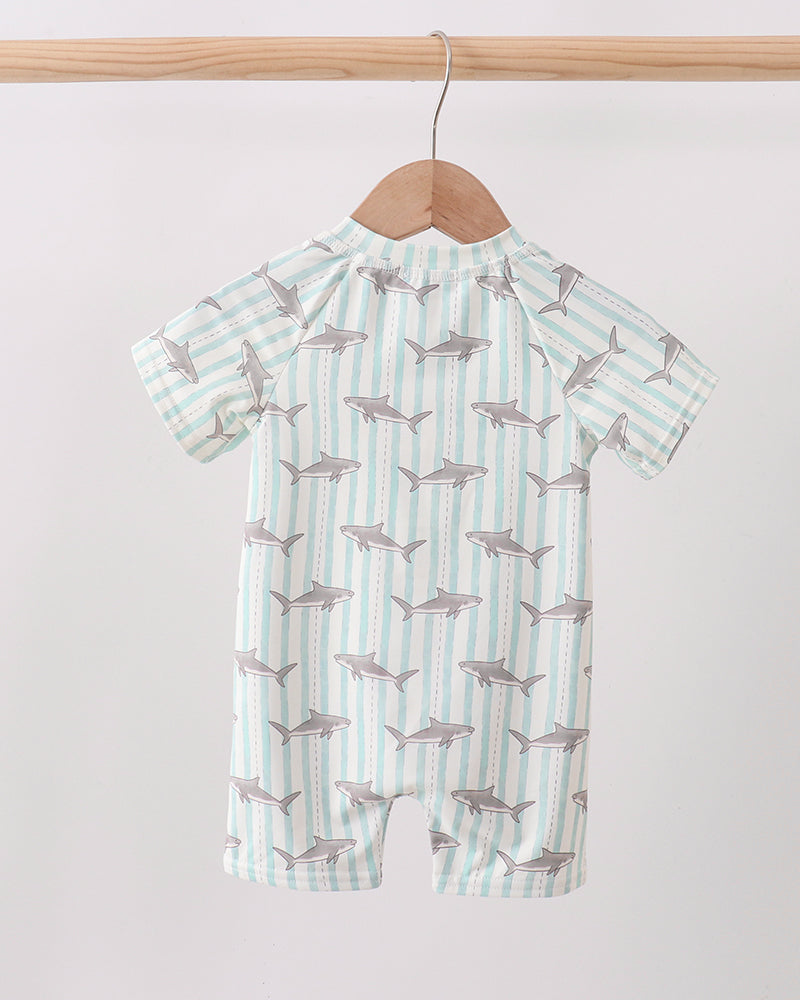 Baby swimsuit with shark pattern on a hanger against a white background
