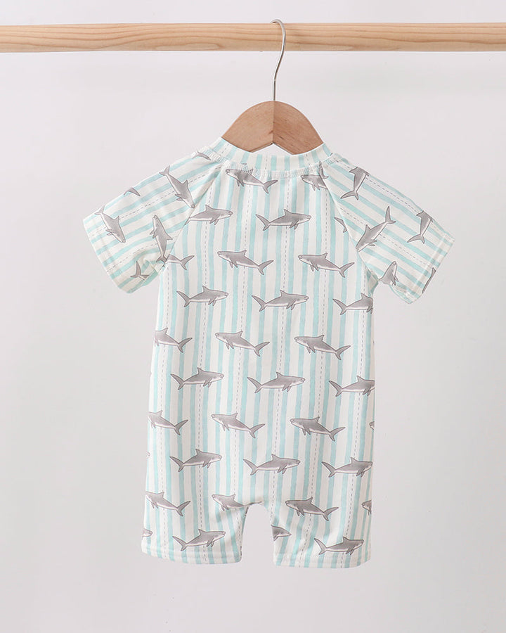 Baby swimsuit with shark pattern on a hanger against a white background