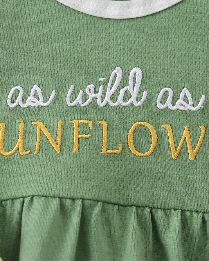 Green romper close-up: white embroidered text and ruffle collar with gingham trim
