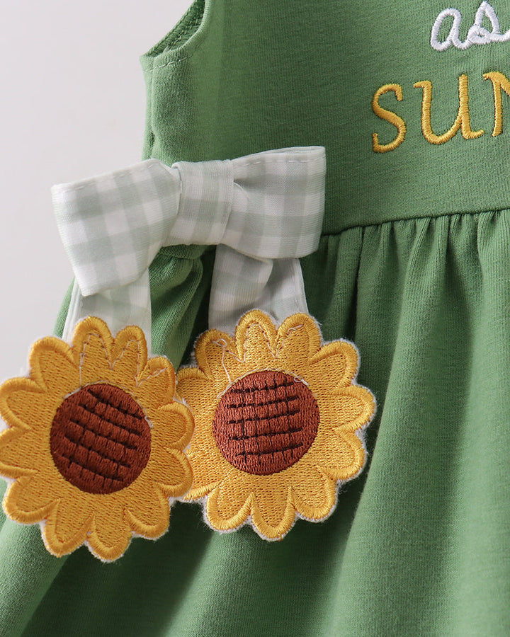 Green dress with two sunflower appliques and small bow accent near hem