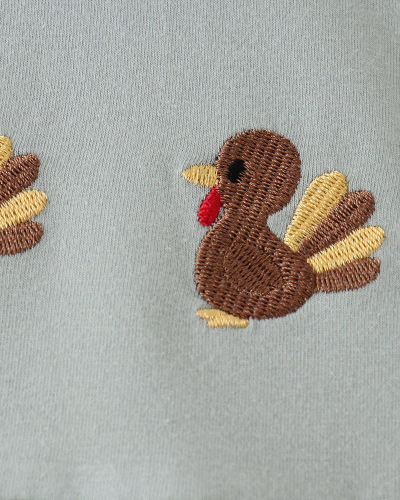 Embroidered turkey patch with multicolor wings on mint green fabric