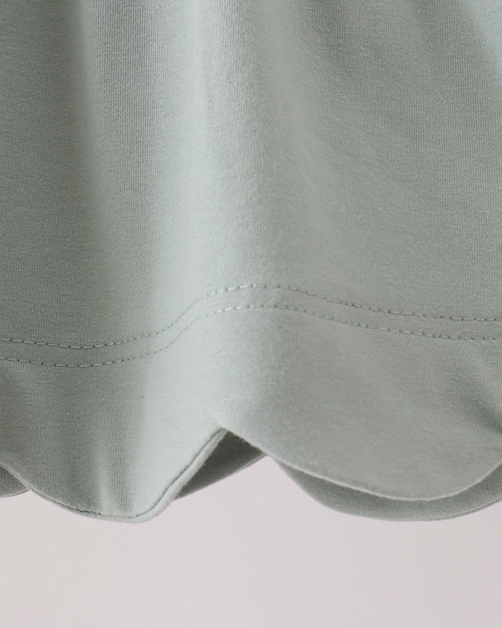 Mint green tunic hem with scalloped edge and double-stitched seam