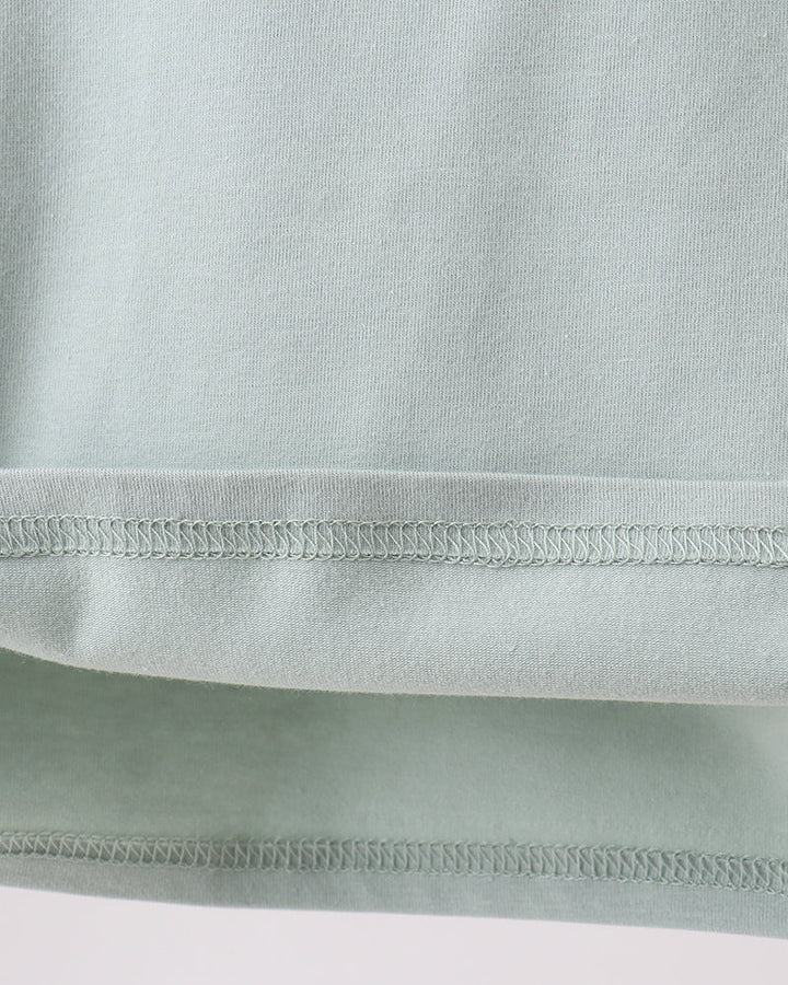 Close-up of a light green fabric with a focus on texture and stitching.