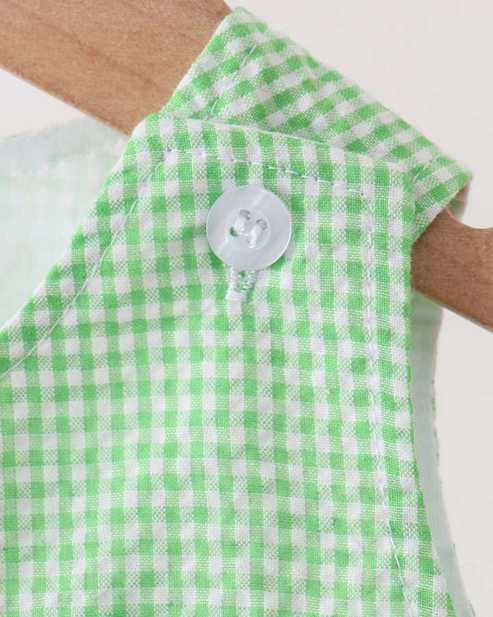 Green and white checkered sleeveless romper with a button on a neutral background