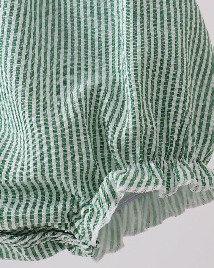 Green and white striped fabric with ruffled edge on a light background
