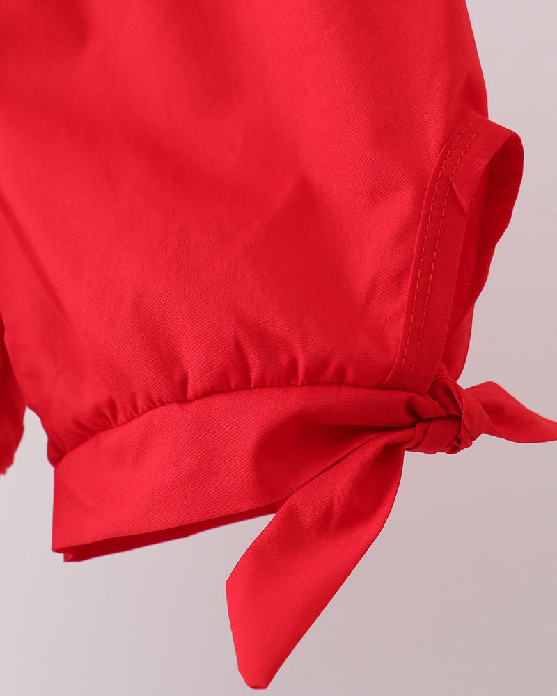 Red shorts with a tie detail on a light gray background